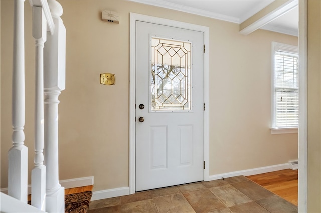 foyer entrance with plenty of natural light, baseboard heating, crown molding, and baseboards