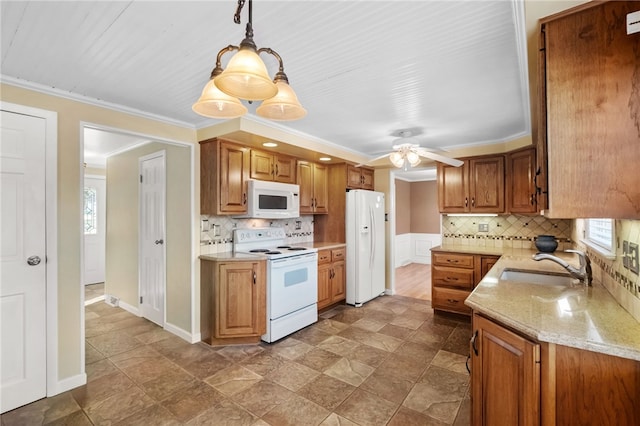 kitchen with a sink, white appliances, tasteful backsplash, and ornamental molding