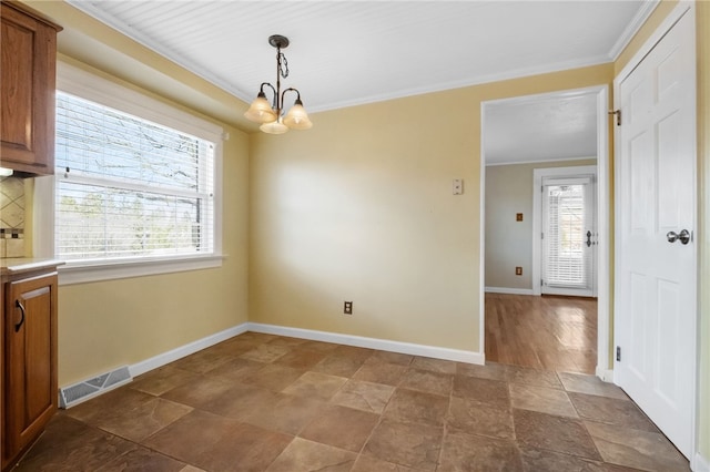 unfurnished dining area with baseboards, visible vents, an inviting chandelier, ornamental molding, and stone finish flooring