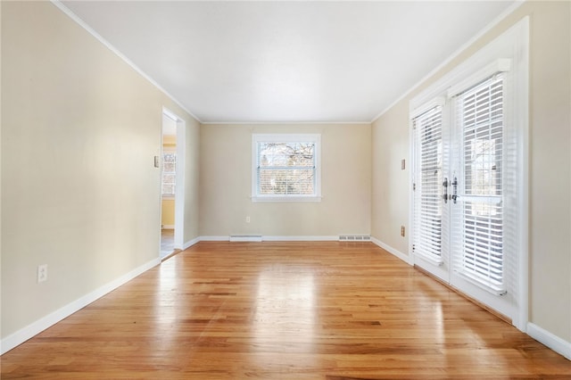 empty room featuring a baseboard radiator, ornamental molding, visible vents, and light wood-type flooring