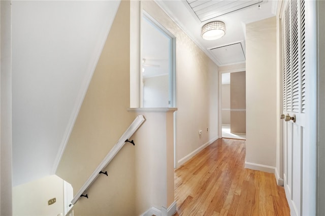 hall with attic access, light wood-style flooring, an upstairs landing, and baseboards