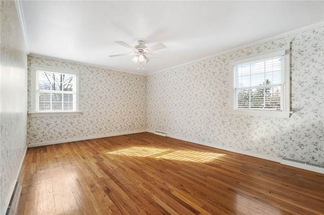 empty room with plenty of natural light, wallpapered walls, baseboards, and hardwood / wood-style flooring