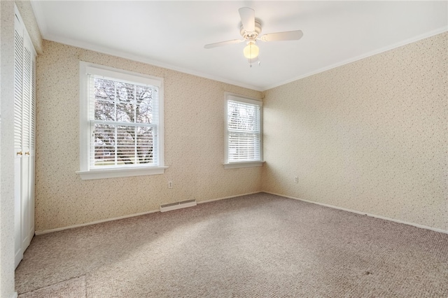 carpeted empty room featuring a baseboard radiator, ornamental molding, a ceiling fan, and wallpapered walls