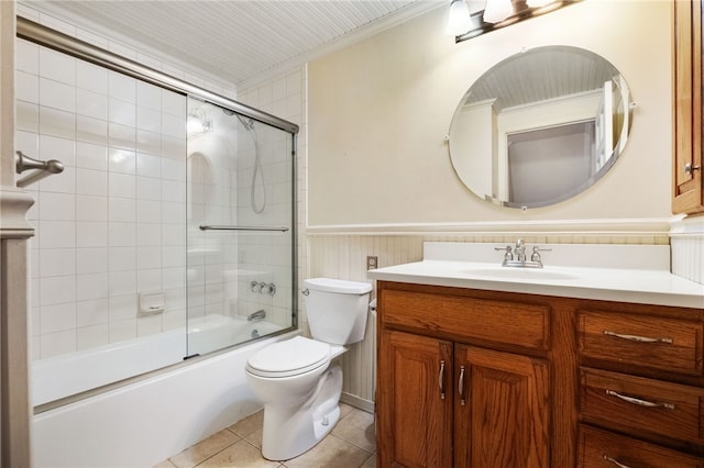 bathroom with toilet, tile patterned flooring, wainscoting, crown molding, and vanity