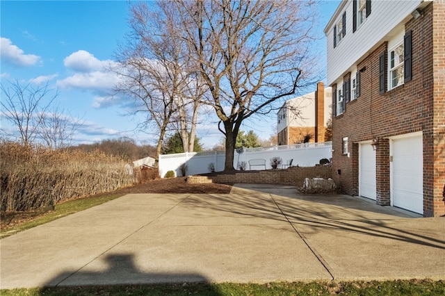 view of yard featuring driveway, an attached garage, and fence