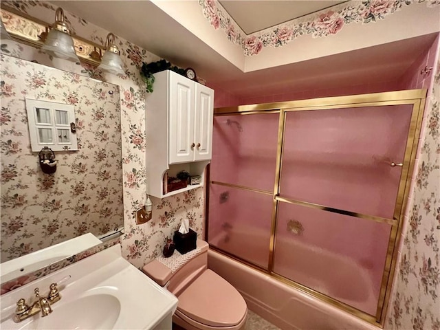 bathroom featuring combined bath / shower with glass door, toilet, wallpapered walls, and vanity