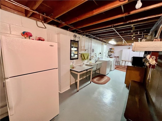 unfinished basement featuring washing machine and dryer and freestanding refrigerator