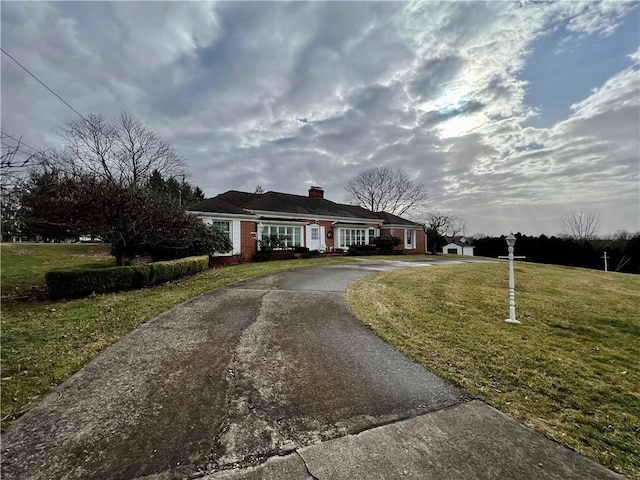 view of front of property featuring aphalt driveway, a chimney, and a front yard