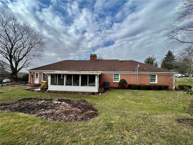 back of house with a lawn, a sunroom, brick siding, central AC unit, and a chimney