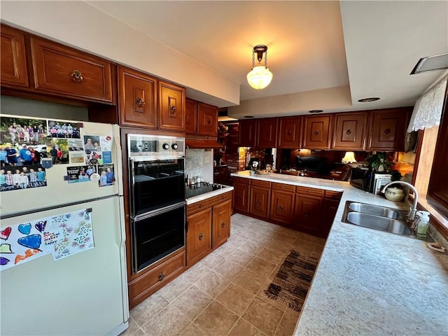 kitchen featuring brown cabinetry, a sink, black appliances, light countertops, and tasteful backsplash