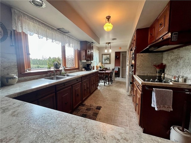 kitchen with a sink, decorative light fixtures, tasteful backsplash, light countertops, and black electric cooktop