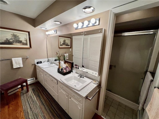 bathroom with double vanity, a stall shower, and a sink