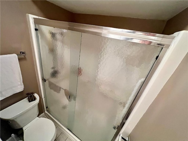 full bathroom featuring a shower with door and toilet