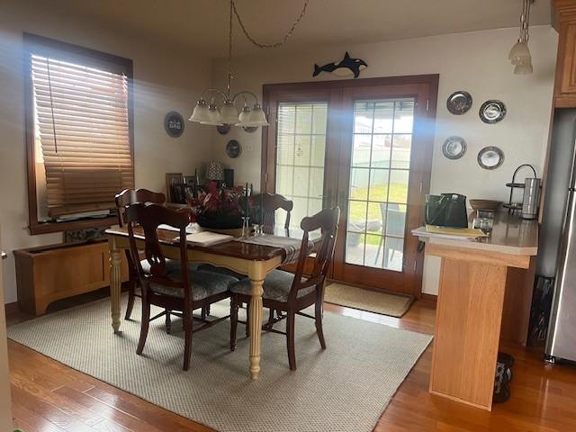 dining space with a notable chandelier, plenty of natural light, and wood finished floors