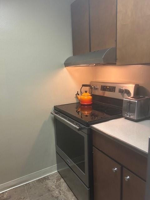 kitchen featuring ventilation hood, dark brown cabinetry, light countertops, stainless steel electric range oven, and baseboards