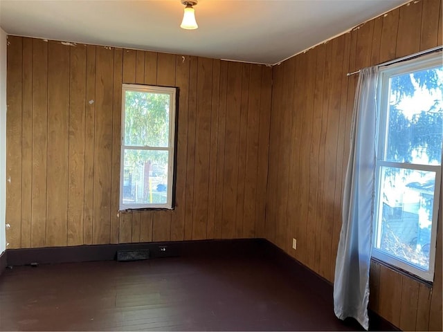 empty room with wood walls and dark wood-style flooring