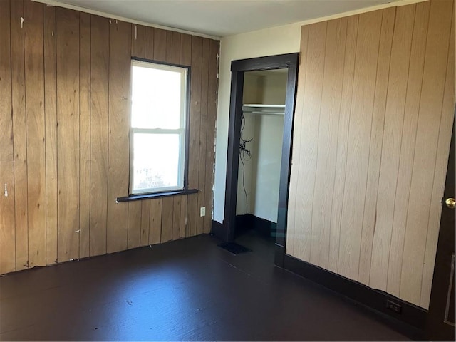 unfurnished bedroom with wooden walls, visible vents, a closet, and finished concrete floors