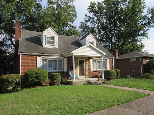 cape cod home with brick siding, a chimney, and a front lawn