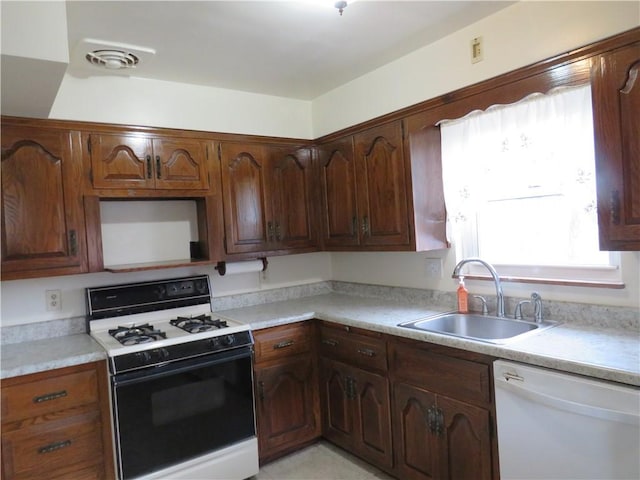 kitchen featuring a sink, visible vents, white appliances, and light countertops