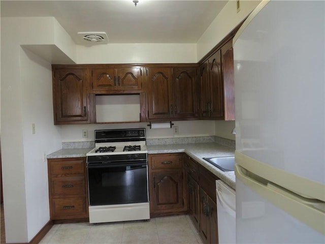 kitchen featuring white appliances, visible vents, light tile patterned flooring, a sink, and light countertops