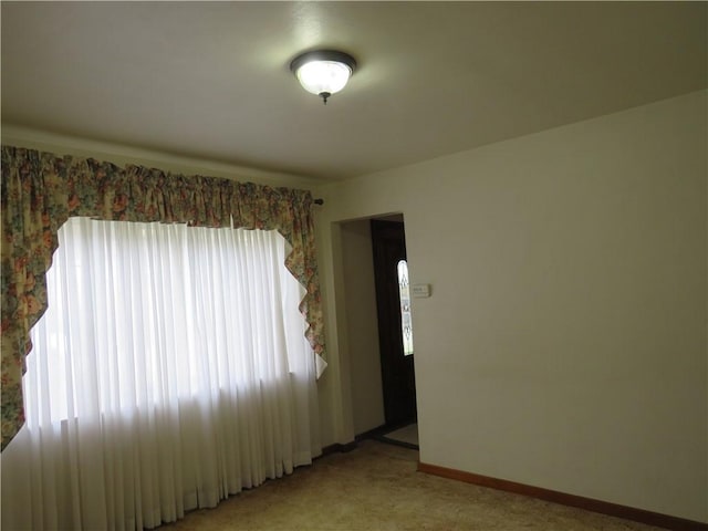 unfurnished room with baseboards and light carpet