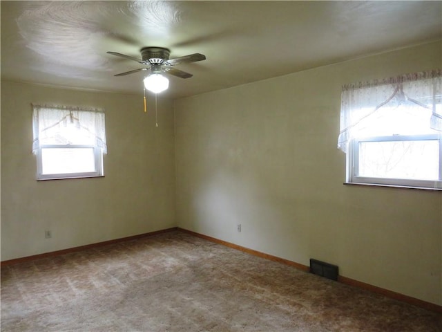 carpeted spare room with baseboards, visible vents, and ceiling fan