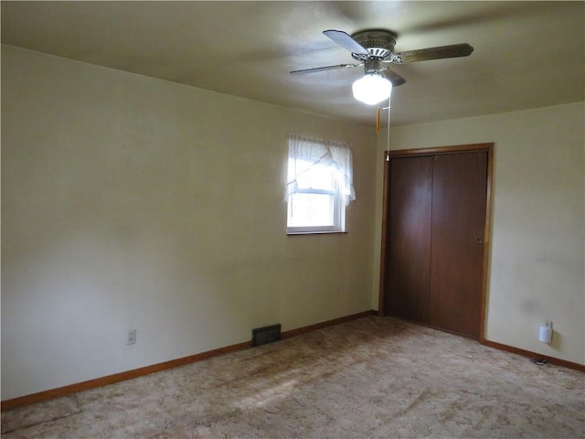 unfurnished bedroom with visible vents, light carpet, a closet, baseboards, and ceiling fan