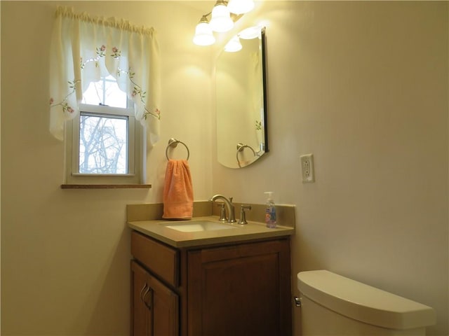 half bath featuring a notable chandelier, toilet, and vanity