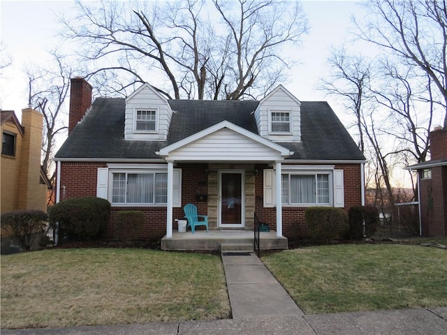 cape cod-style house with brick siding, covered porch, a chimney, and a front lawn