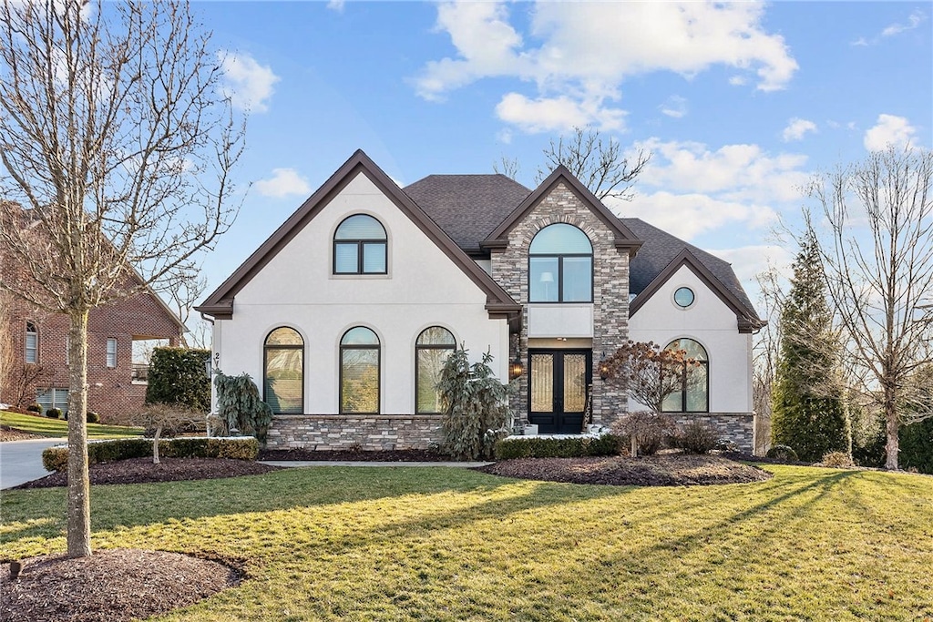 french country inspired facade with stone siding, stucco siding, and a front lawn