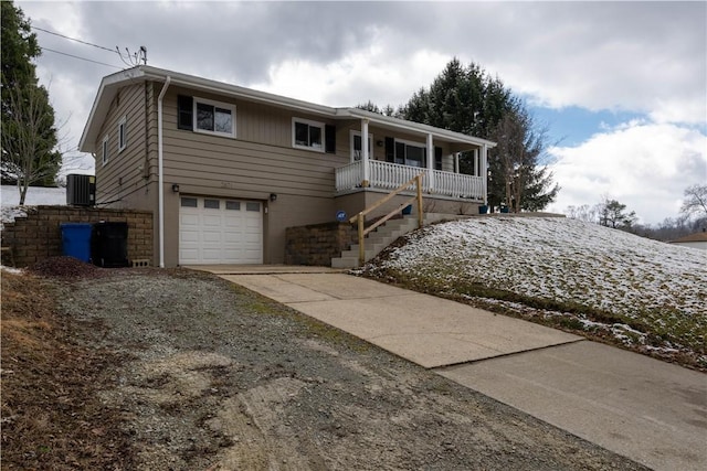 ranch-style house with stairway, central air condition unit, concrete driveway, covered porch, and a garage