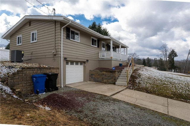 view of side of property featuring stairway, central AC unit, concrete driveway, and an attached garage