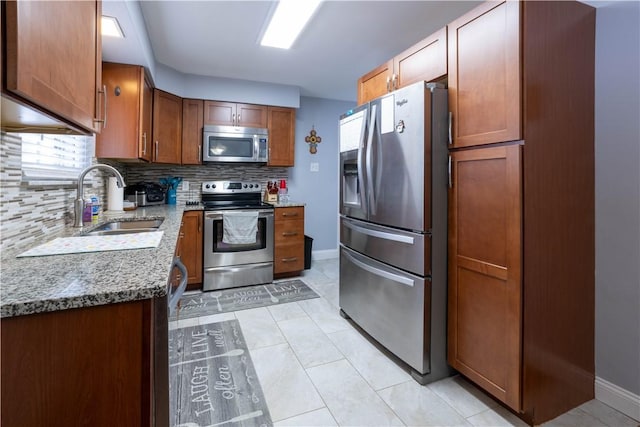 kitchen with light tile patterned floors, a sink, appliances with stainless steel finishes, tasteful backsplash, and brown cabinets