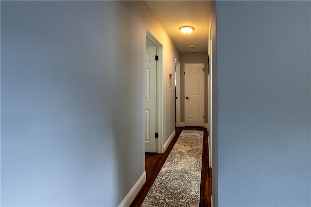 hallway with dark wood-type flooring and baseboards