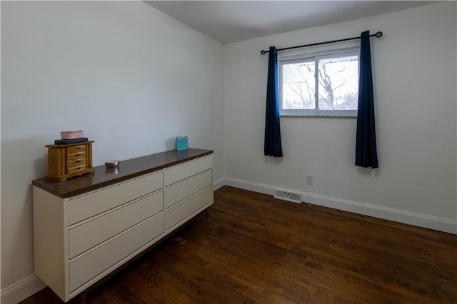 unfurnished bedroom featuring visible vents, baseboards, and dark wood finished floors