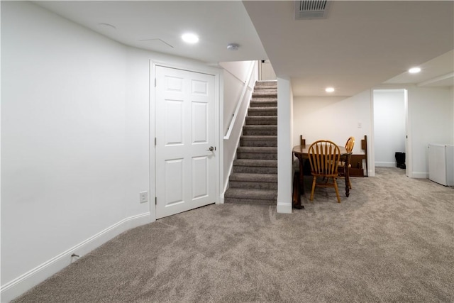 finished below grade area with visible vents, baseboards, carpet, and stairway