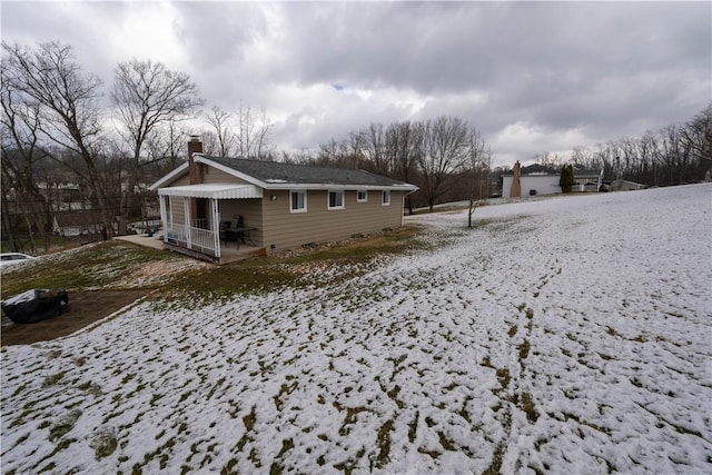 snow covered back of property featuring a chimney