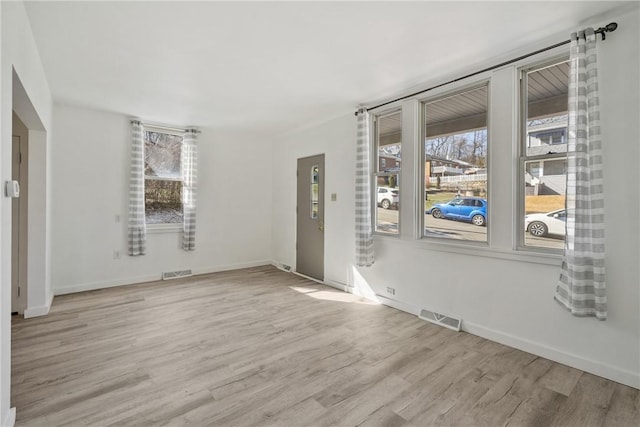 empty room featuring visible vents, baseboards, and light wood-style floors