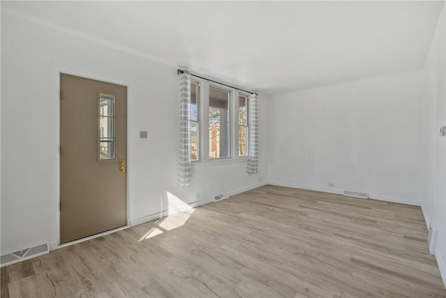 empty room featuring wood finished floors, visible vents, and baseboards