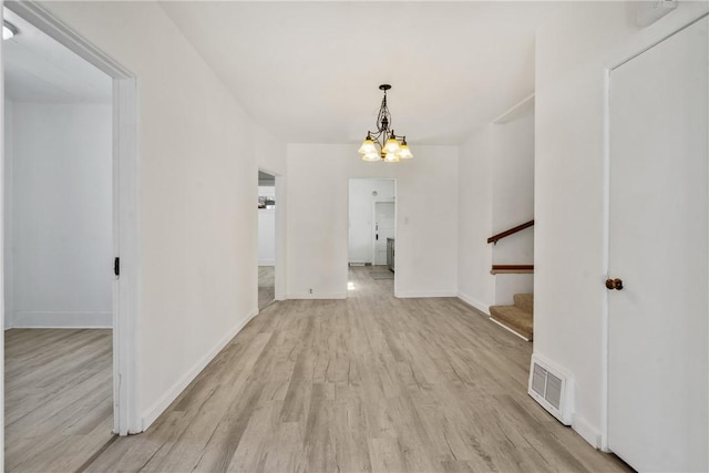 foyer entrance with visible vents, light wood-style flooring, stairway, baseboards, and a chandelier