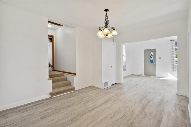 interior space with light wood-type flooring, baseboards, visible vents, and stairway