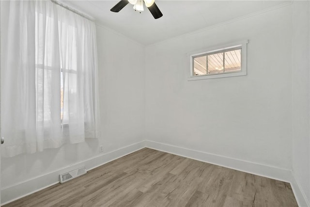 unfurnished room featuring visible vents, wood finished floors, baseboards, and ornamental molding