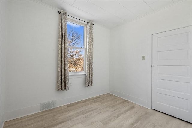 empty room with baseboards, visible vents, and light wood finished floors