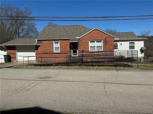 view of front of home with a garage, fence, brick siding, and roof with shingles