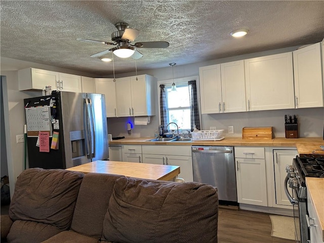 kitchen featuring a sink, open floor plan, stainless steel appliances, white cabinets, and dark wood-style flooring