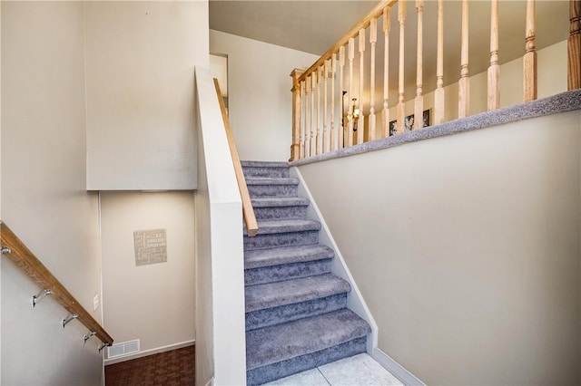 stairway featuring baseboards and visible vents