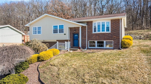 raised ranch with brick siding, an attached garage, and a front yard