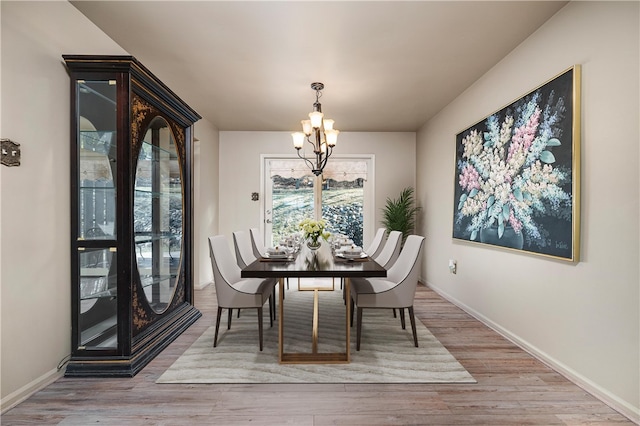 dining space featuring a notable chandelier, wood finished floors, and baseboards