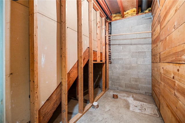 interior space featuring concrete block wall and unfinished concrete flooring