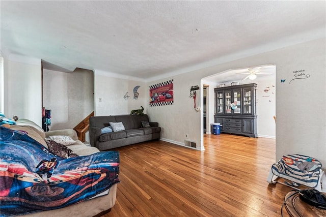 living room with baseboards, wood finished floors, visible vents, and arched walkways